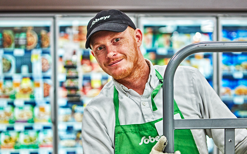 Un employé de Sobeys qui remplit des tablettes d’aliments surgelés.