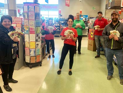 Un groupe d’employés et de clients de Foodland qui tiennent des cartes-cadeaux en respectant la distanciation physique.