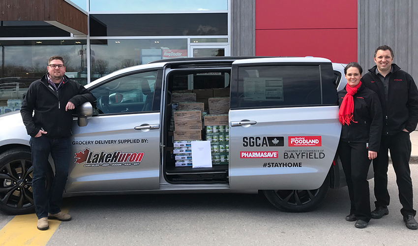 Employés de Foodland à côté d’un camion de livraison rempli de produits d’épicerie.